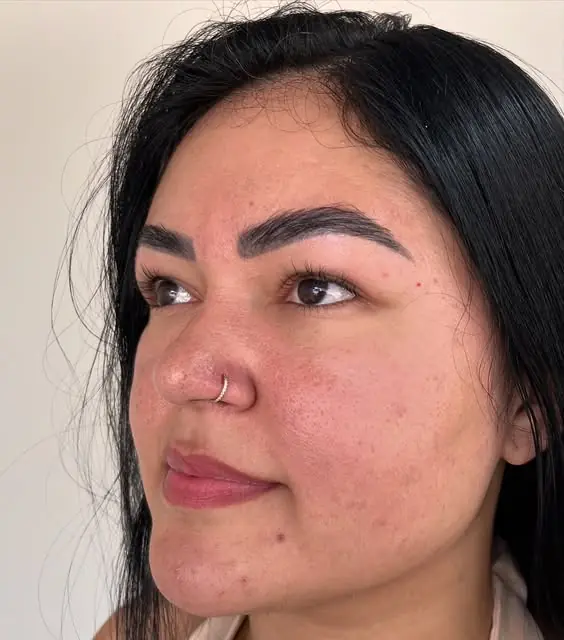 Mulher de perfil com uma argola fina na aba do nariz