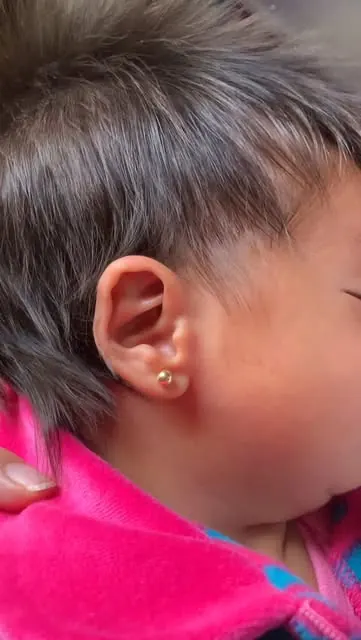 Bebê com um brinco pequeno dourado na orelha